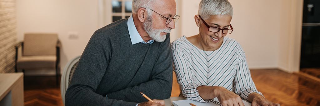 A retired couple uses a calculator while reviewing tax-deferred annuity options.