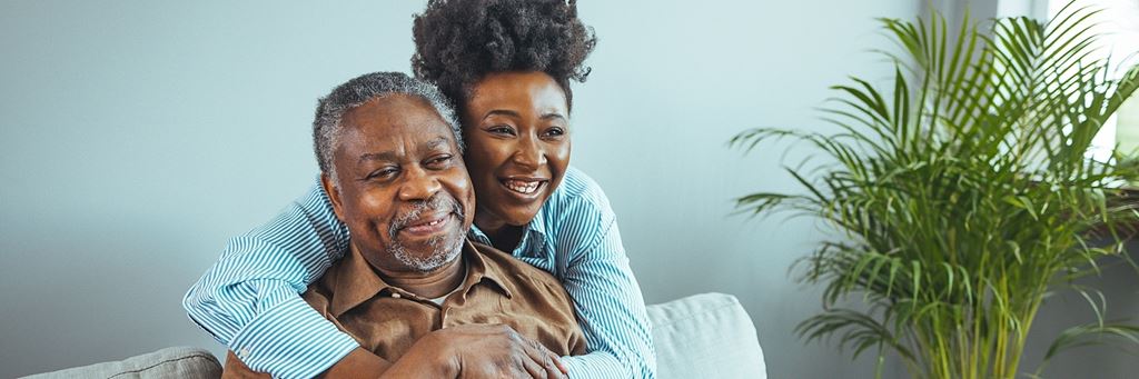Adult daughter embraces her older father.