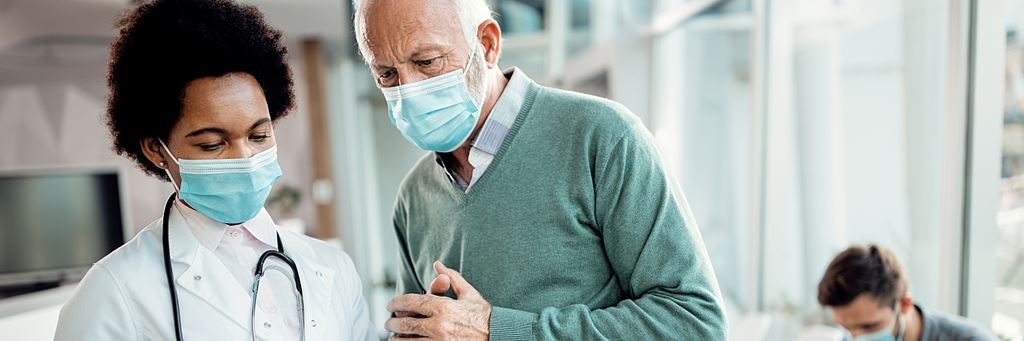 A doctor shows a senior patient his health information on a digital tablet.