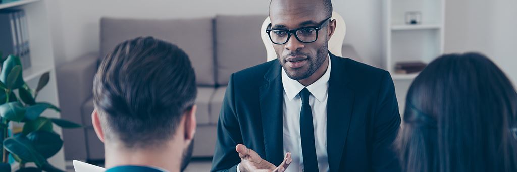 A lawyer speaks with a couple about being a named beneficiary in a will.