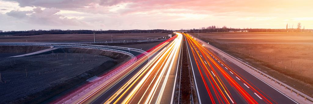 An aerial timelapse shot of a highway with cars driving in multiple lanes.
