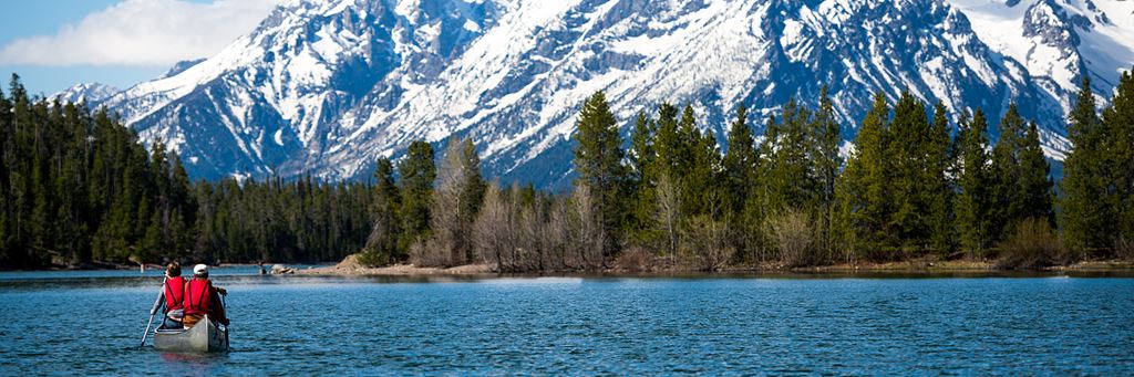 A couple canoes on a lake in front of a mountain.