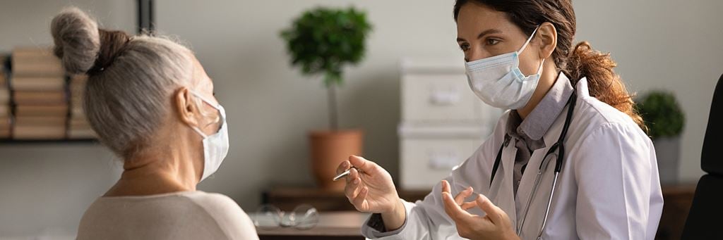 A doctor speaks with a senior patient about the difference between HMO and PPO plans.