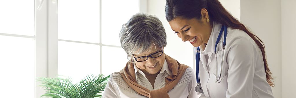A senior woman and her doctor look at paperwork together.