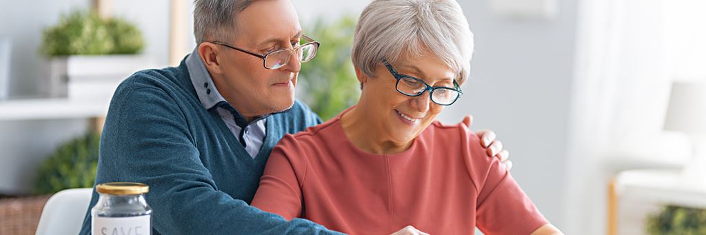 A senior couple looking at their paychecks and calculating payroll taxes.