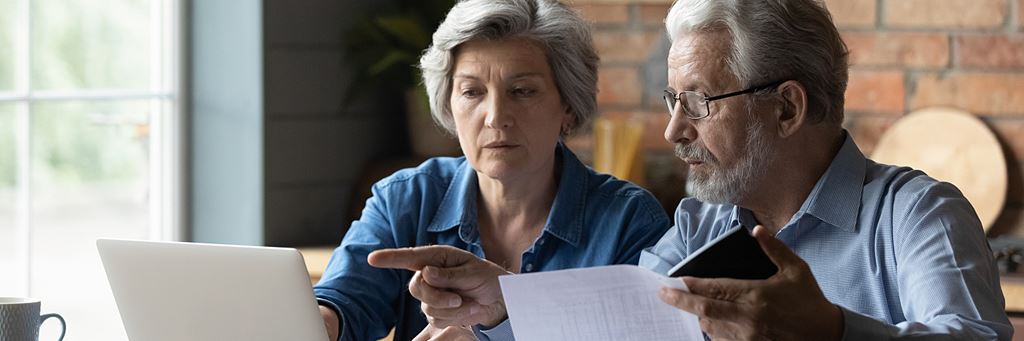 An older couple uses a laptop to learn the best ways to invest for retirement.