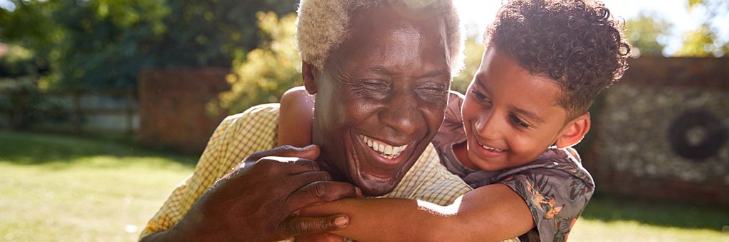 A smiling grandfather being hugged by his grandson.