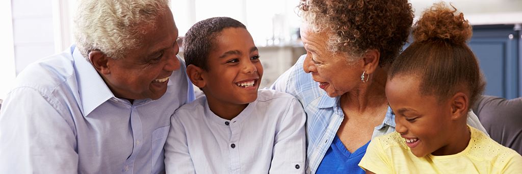 Two grandparents sitting and laughing with their two grandchildren.