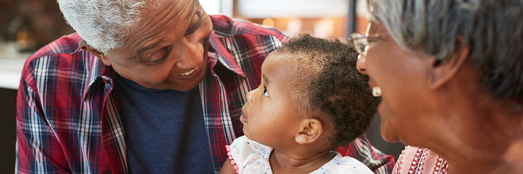 Two grandparents read to their granddaughter.