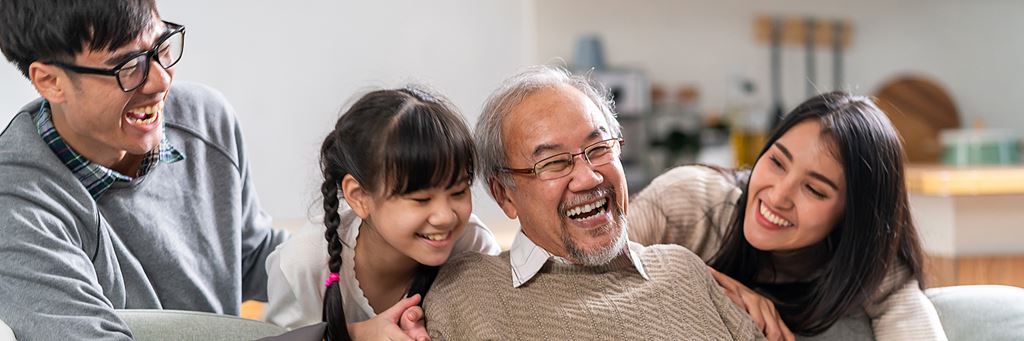 A multigenerational family laughs together on a couch.