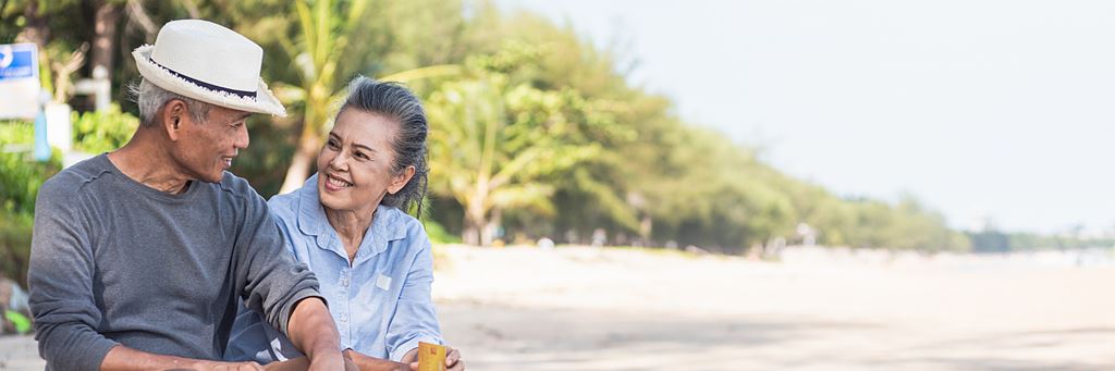 Two happy seniors relax on a beach.