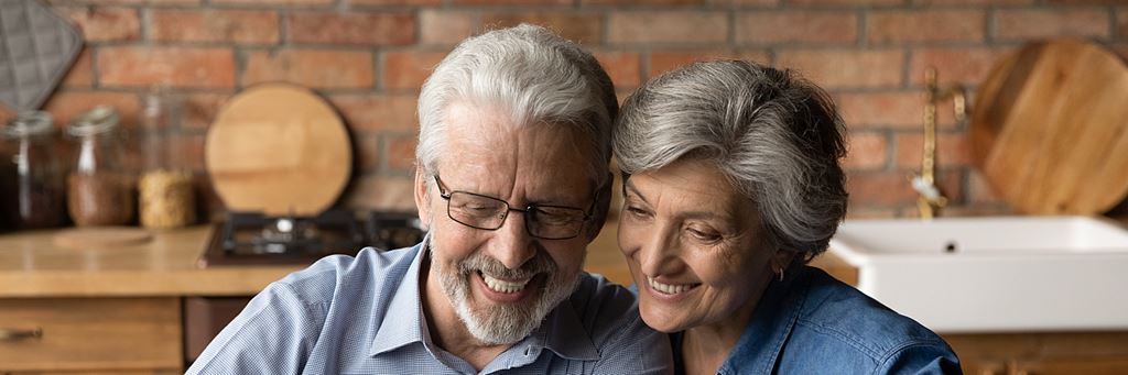 A senior couple reviewing health care plans on laptop.
