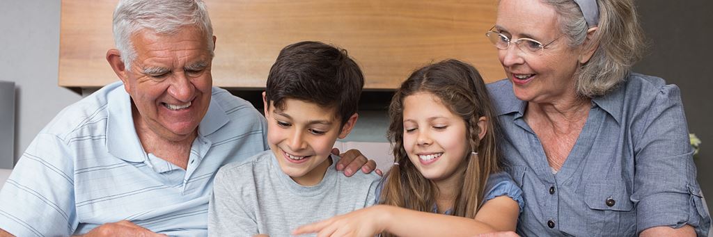 Two grandparents sit with their smiling two grandkids.