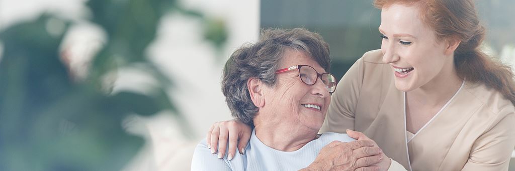 A senior woman with a caretaker in a short-term care facility.