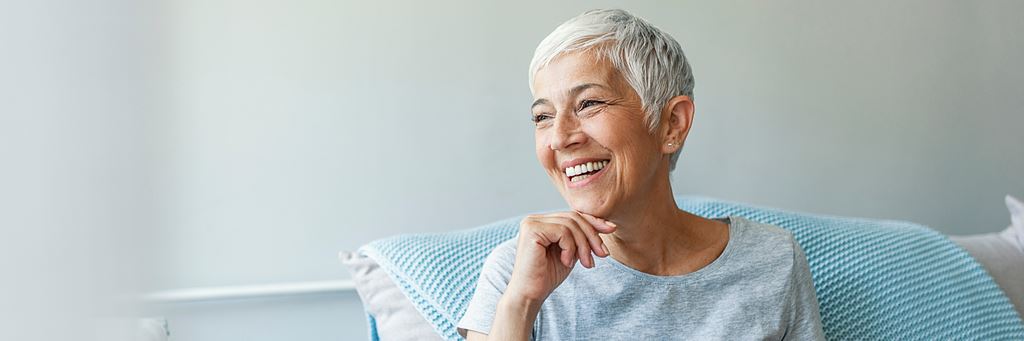 A smiling senior sits on the couch.