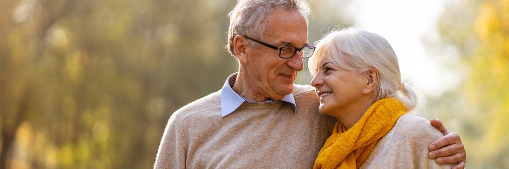 A happy retired couple walks together outdoors.