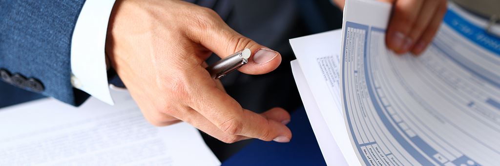 A business person in a suit flips through various insurance papers.