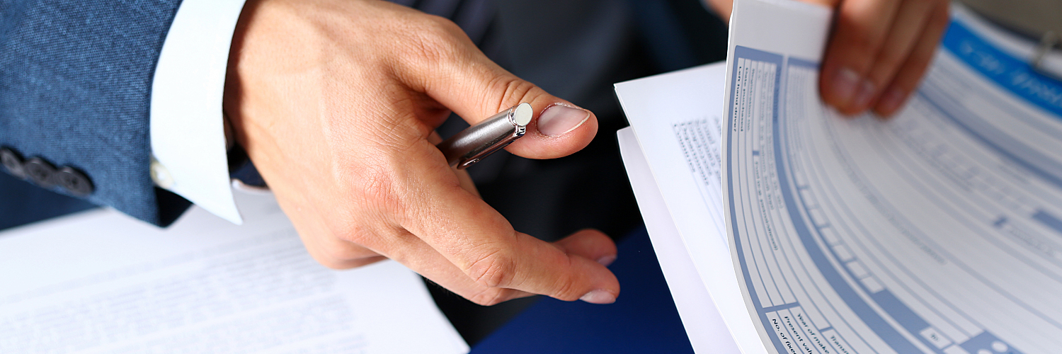 A business person in a suit flips through various insurance papers.