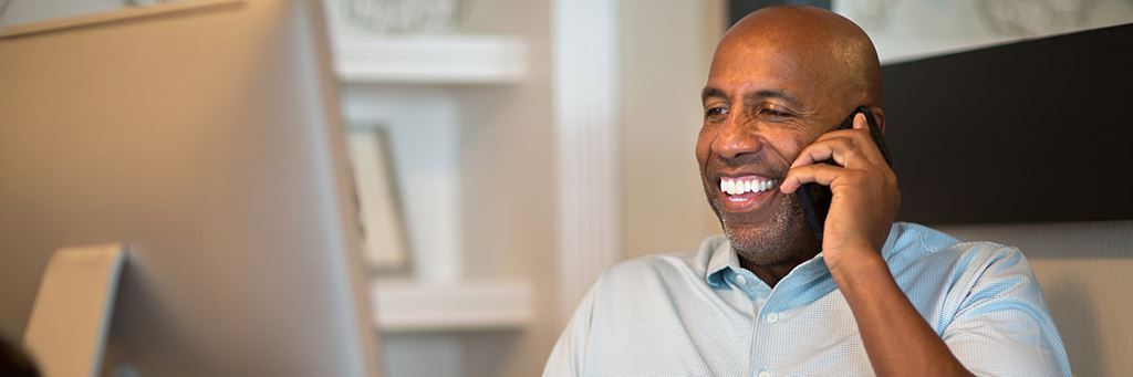 A man smiles while he talks on the phone and sets up his SEP-IRA account.