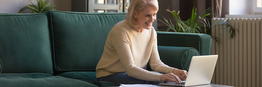 An older woman types a retirement letter on her laptop.