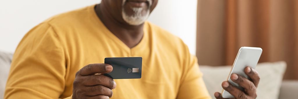 A man uses his credit card to purchase something on his phone.