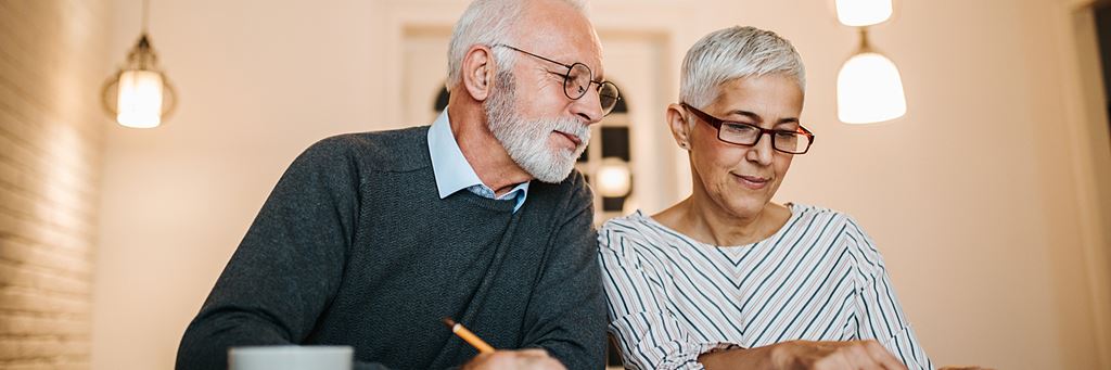 A senior couple with a computer and documents planning for retirement.
