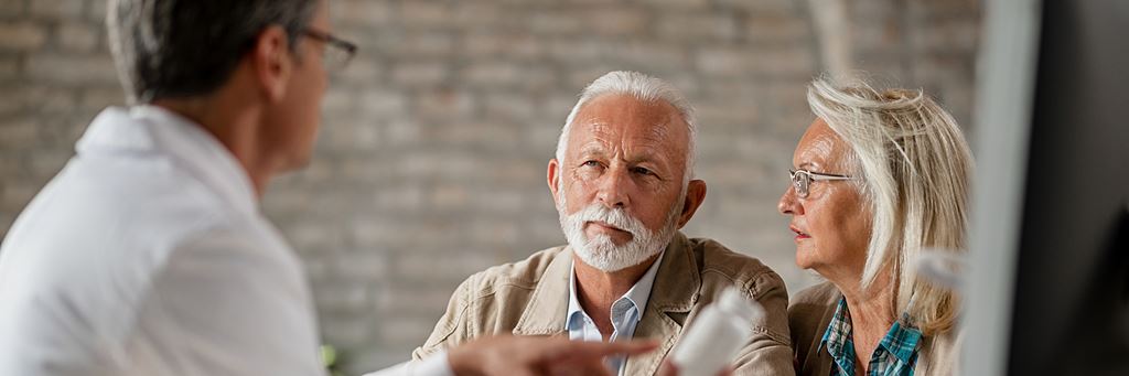 Two seniors speak to a doctor about Medicare coverage.