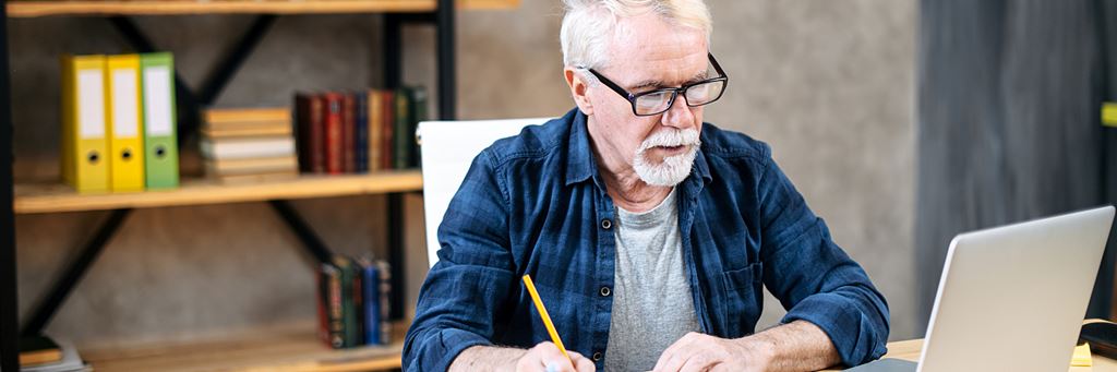 A senior man uses a laptop for research on annuity payout options.