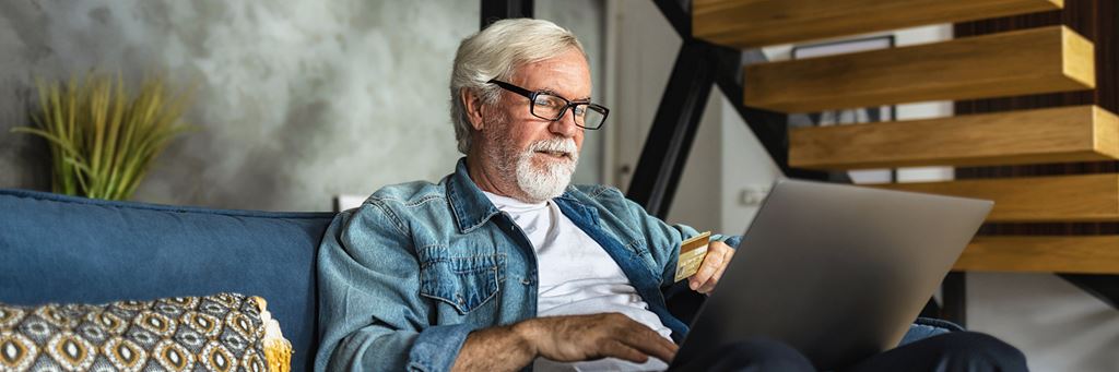A senior uses a laptop to check on his financial accounts.