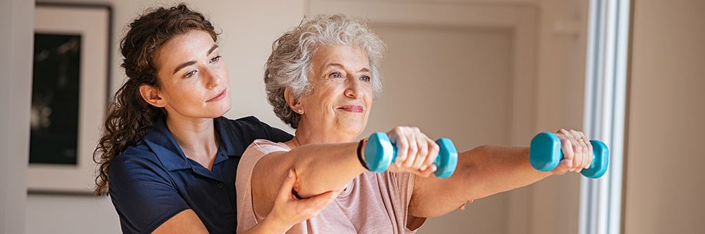 A nurse assists a senior with physical therapy at a short-term care facility.