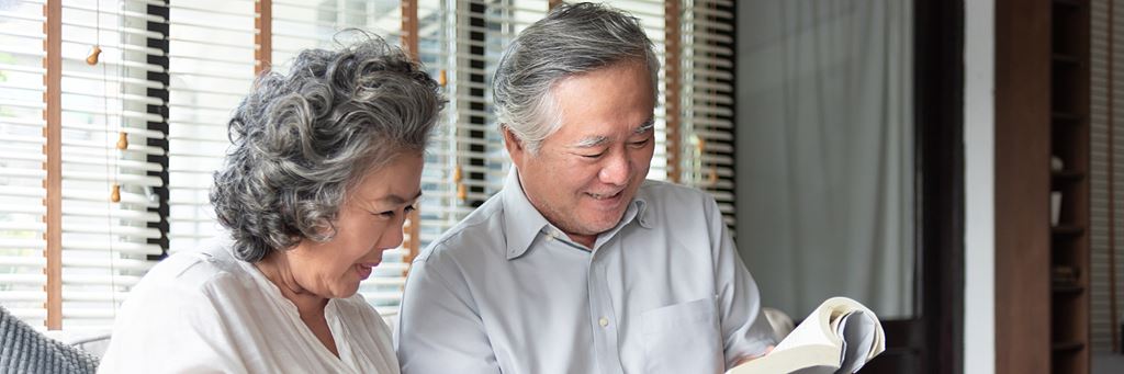 An older couple reads a book together.