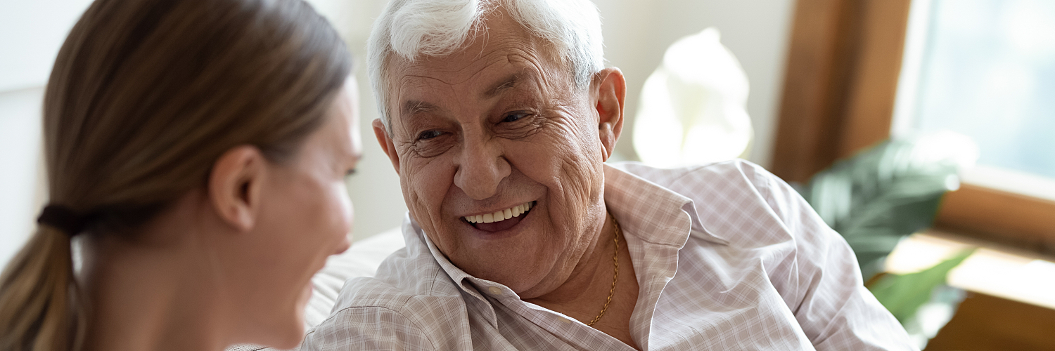 An older man sits with his daughter and smiles.