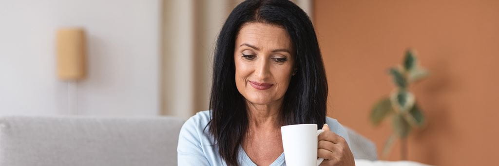 An older woman drinking a cup of tea.
