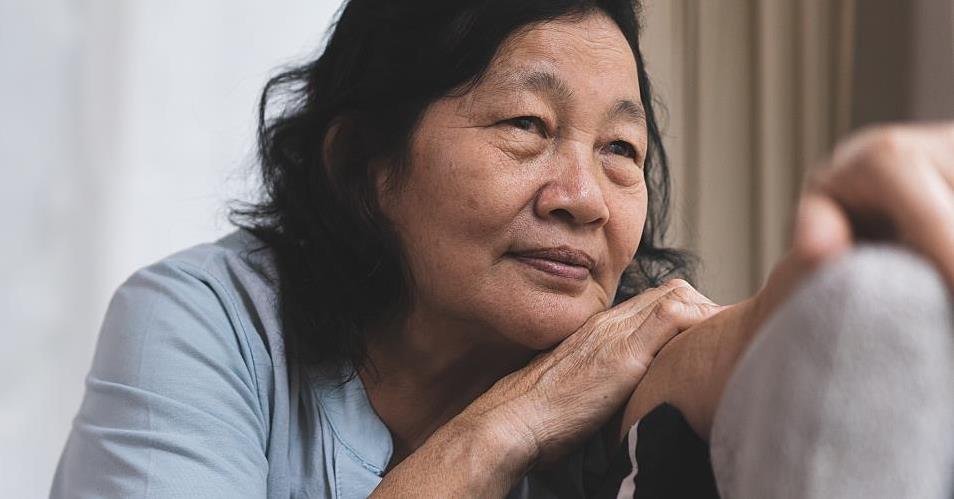 An older woman looks out a window.