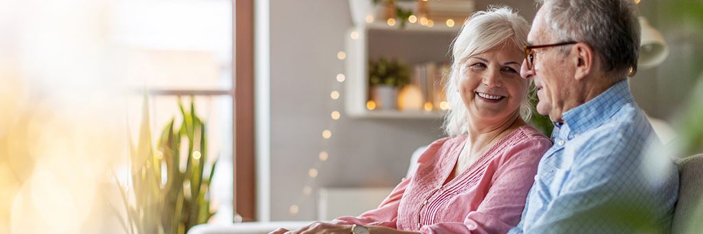 A senior couple talks about health-related home renovations in their living room.