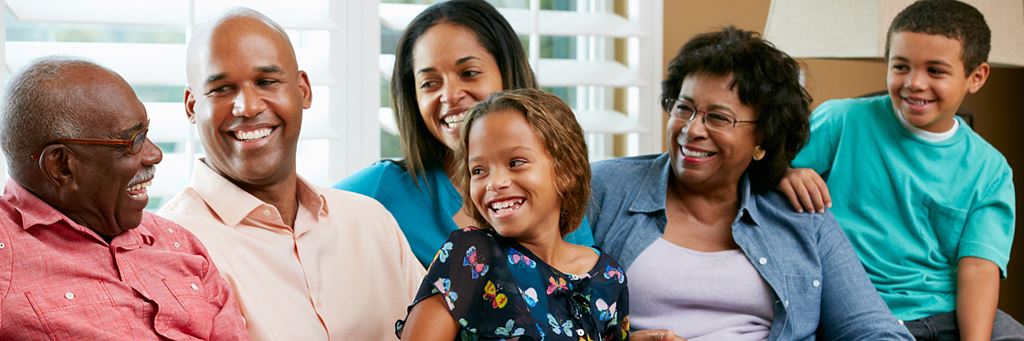 A multigenerational family laughs together on a couch.