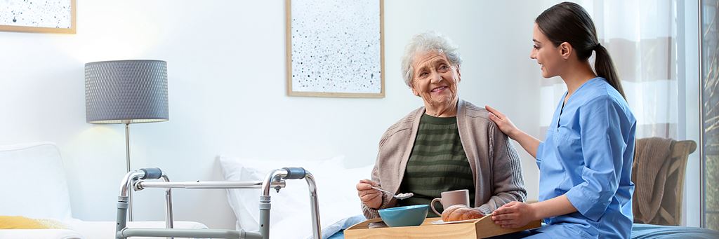 A senior in a nursing home and a caregiver.