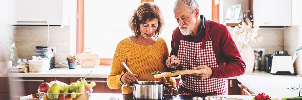 Senior couple cooking together and practicing healthy habits.
