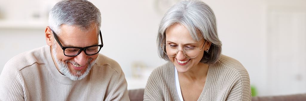 A smiling senior couple looking down at paperwork.