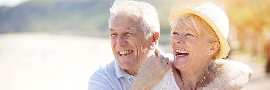 A couple relaxes and smiles on the beach.