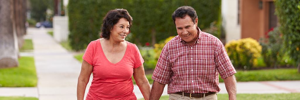 A happy older couple walks in their neighborhood.