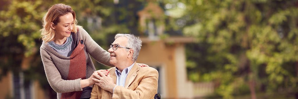 A middle-aged woman spends time with a senior man in a wheelchair.
