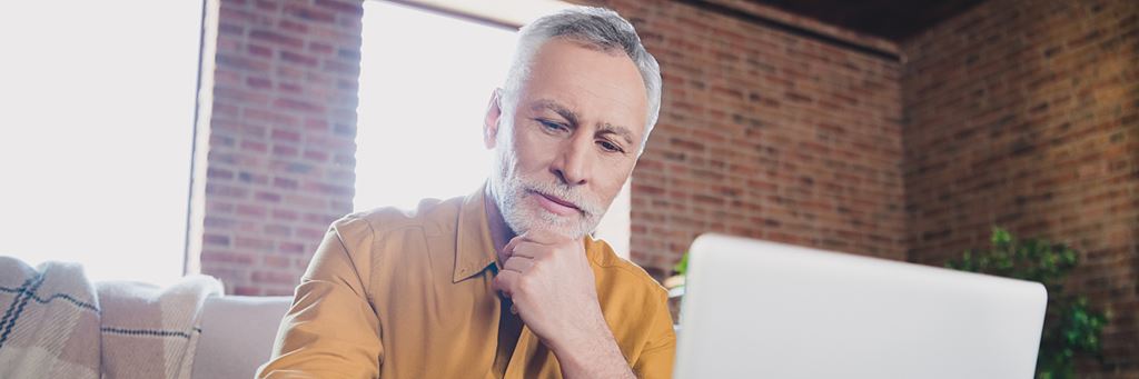 A senior man looks at his computer.