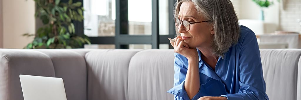 A senior woman uses a laptop to review her financial plans.