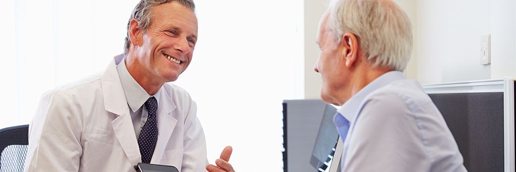 A senior patient talks to a doctor about Medicare coverage during a consultation.