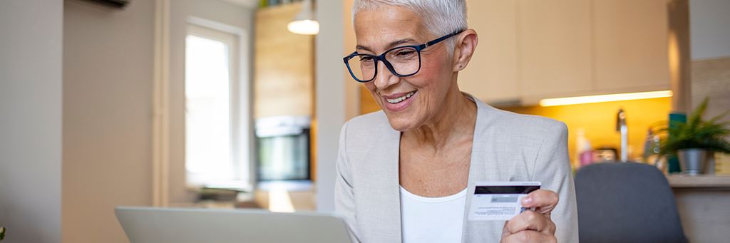 Woman wearing glasses using a credit card on her computer.