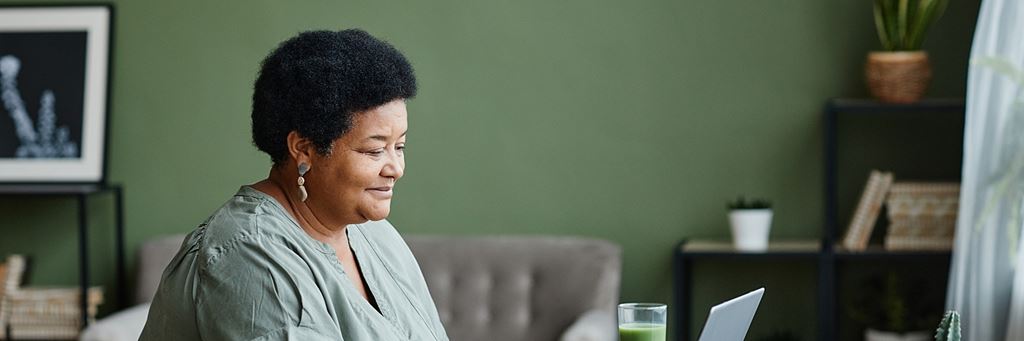 A smiling woman uses a computer.
