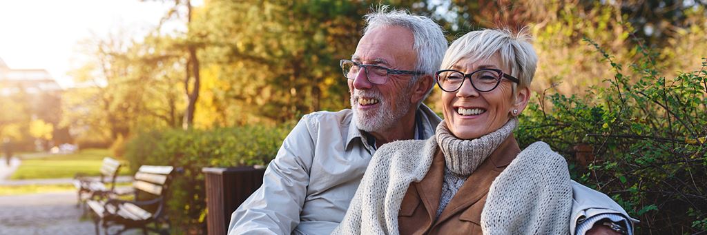 A happy retired couple sitting on bench enjoying the city.