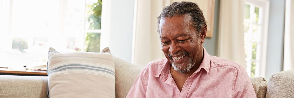 A smiling senior man looks at his computer.