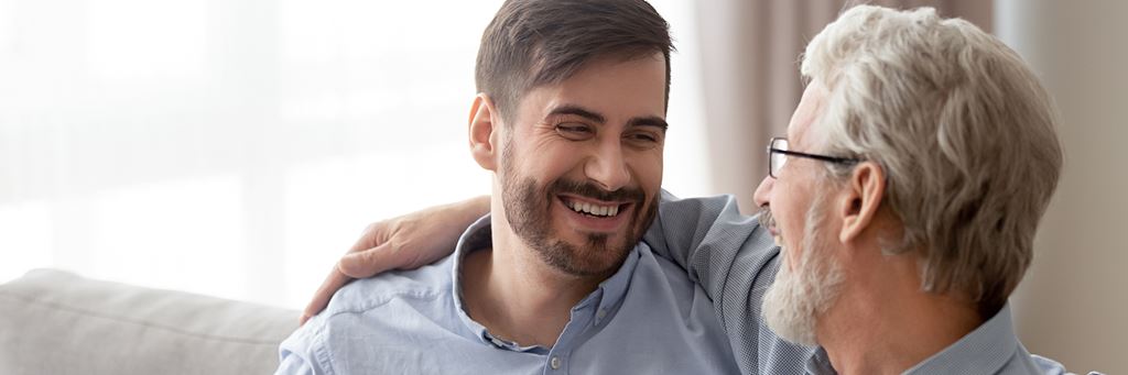 A senior man and his adult son laugh together.